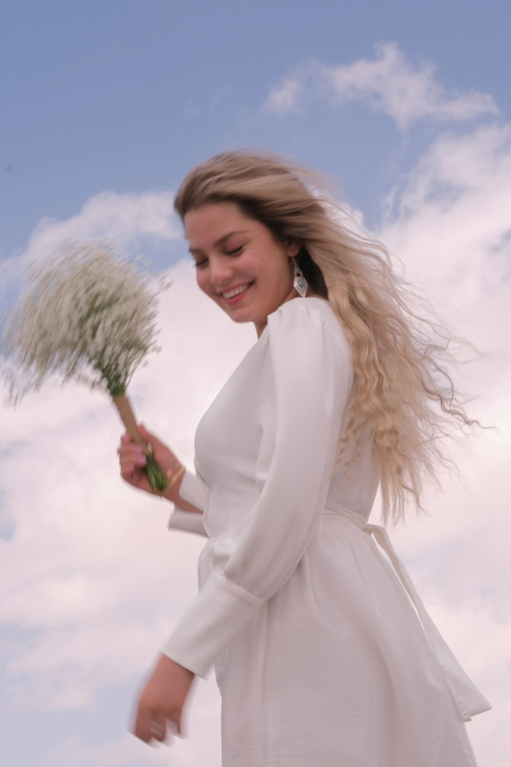 a woman in a white dress holding a bunch of flowers