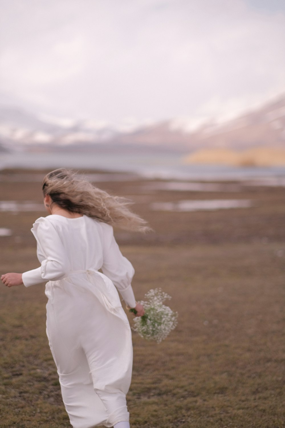 a woman in a white jumpsuit running through a field