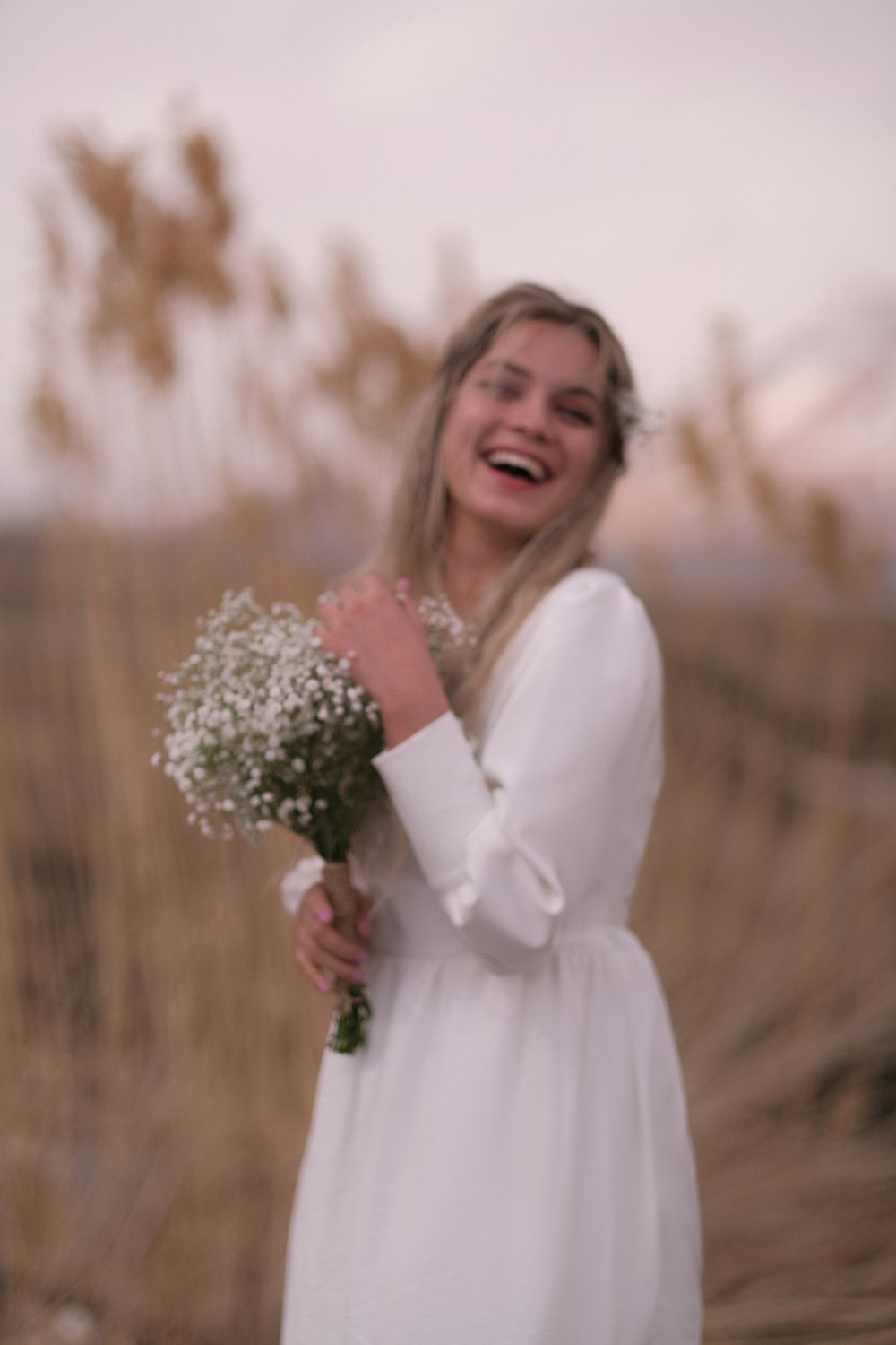 Una mujer con un vestido blanco sosteniendo un ramo de flores