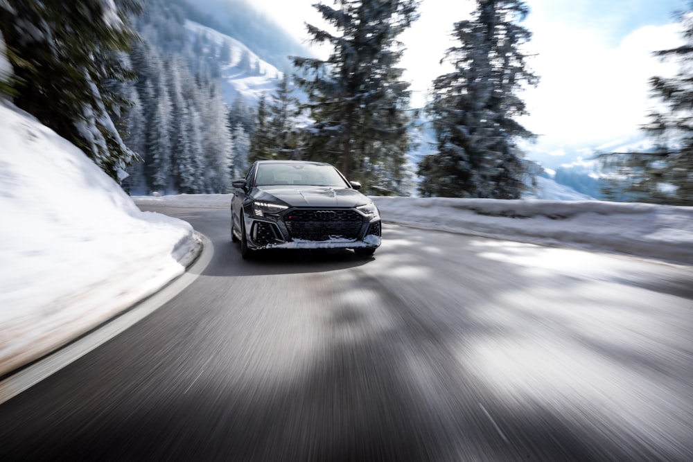 a black car driving down a snowy road