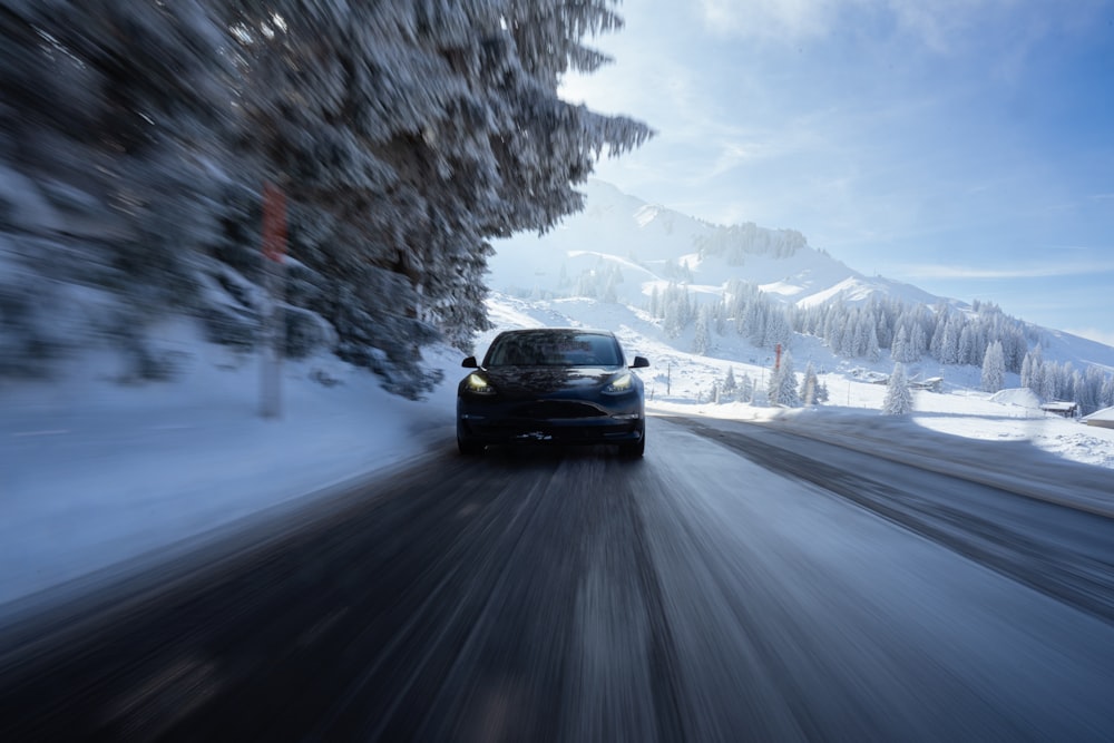 a car driving down a snowy road in the mountains