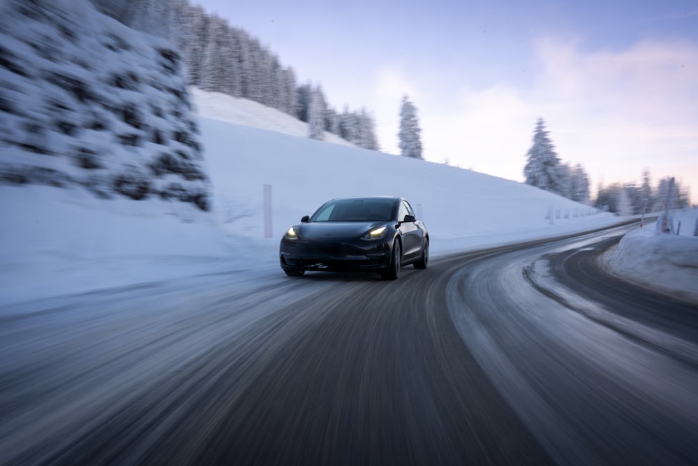 a black car driving down a snowy road