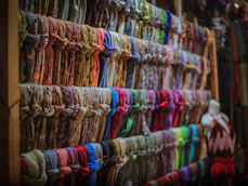 Close-up of colorful scarves and accessories arranged on a rustic wooden table.