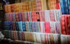 a wall of colorful fabrics hanging on a wall