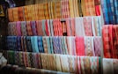 a wall of colorful fabrics hanging on a wall