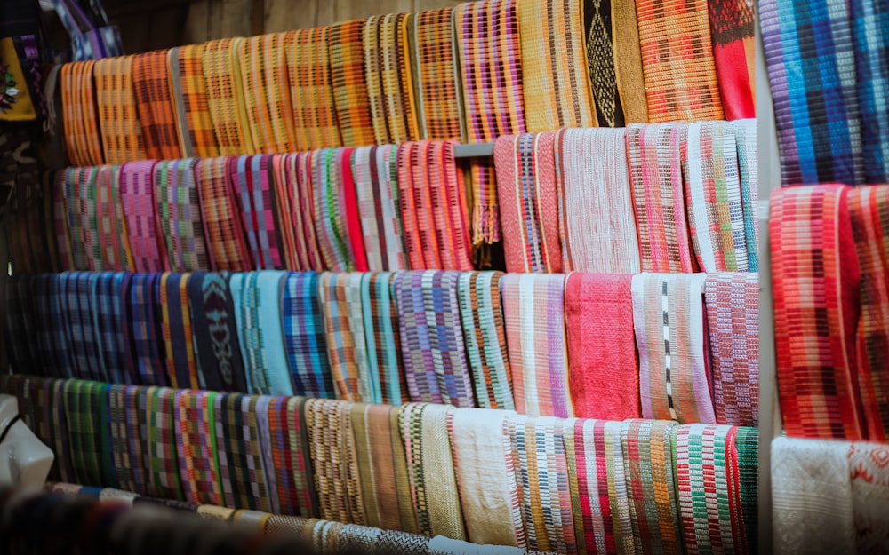 a wall of colorful fabrics hanging on a wall