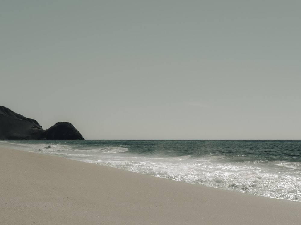 a sandy beach with waves coming in to shore