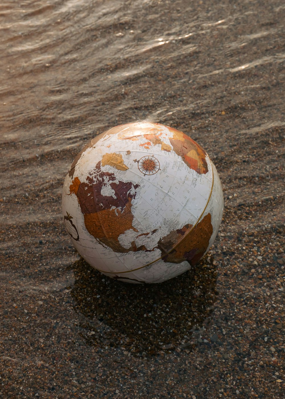 a worn out soccer ball sitting in the sand