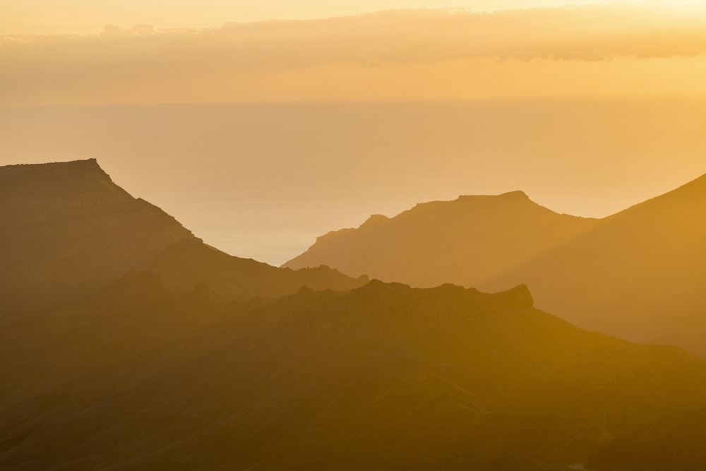 the sun is setting over the mountains in the distance