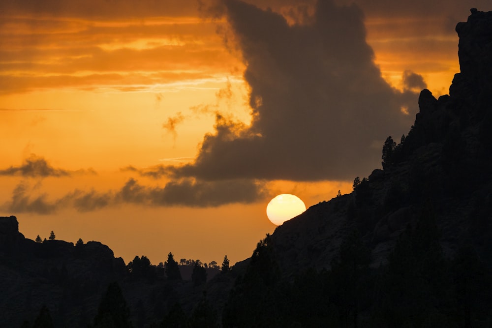 Il sole sta tramontando sulle montagne con una nuvola nel cielo