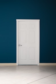 an empty room with a white door and a blue wall