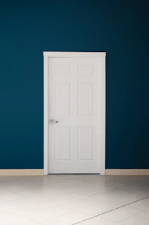 an empty room with a white door and a blue wall