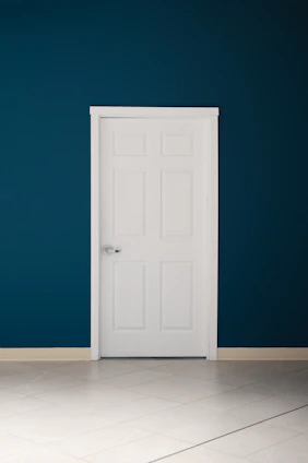 an empty room with a white door and a blue wall