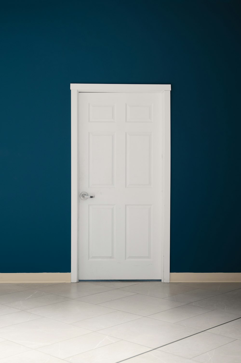 an empty room with a white door and a blue wall