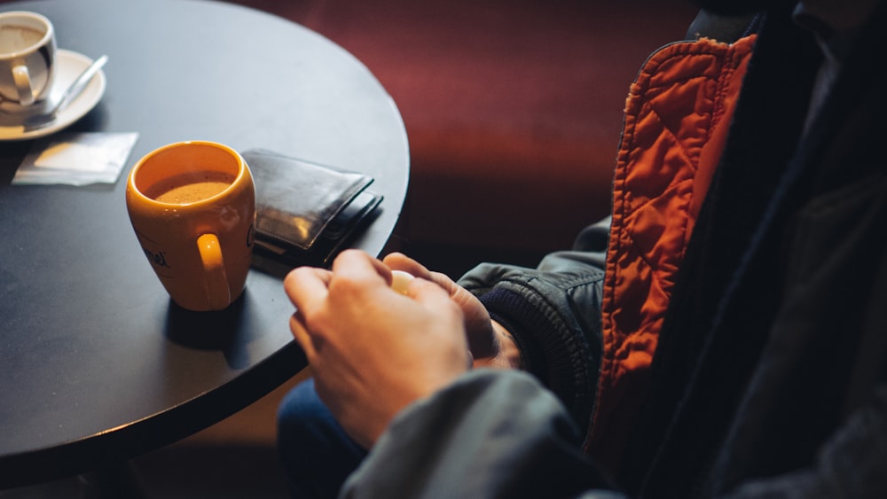 a person sitting at a table with a cup of coffee