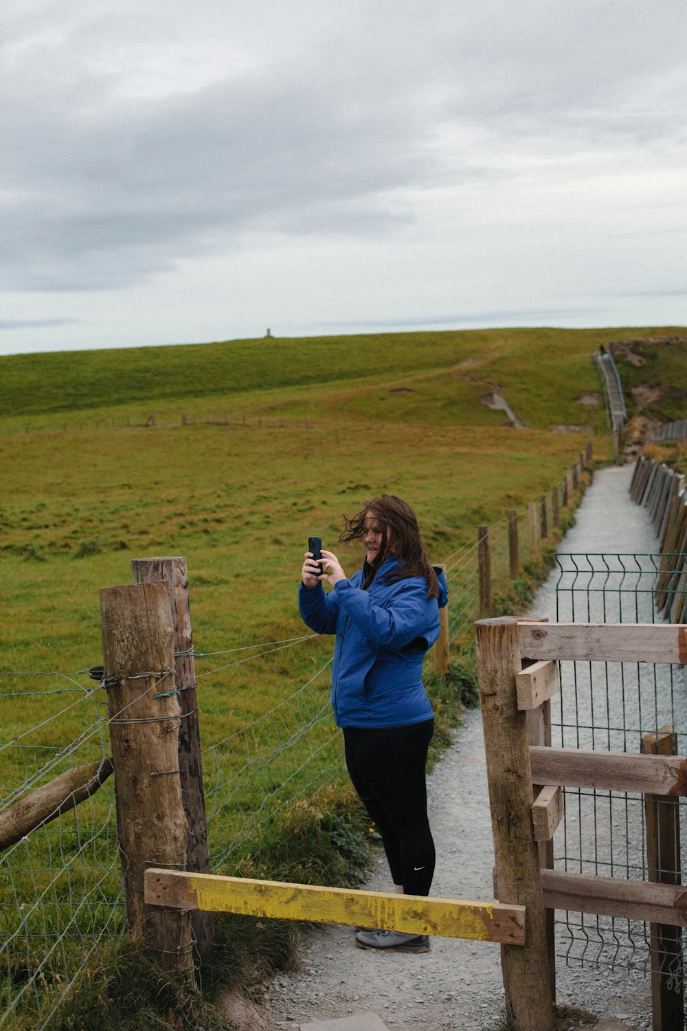 a woman taking a picture of a grassy field