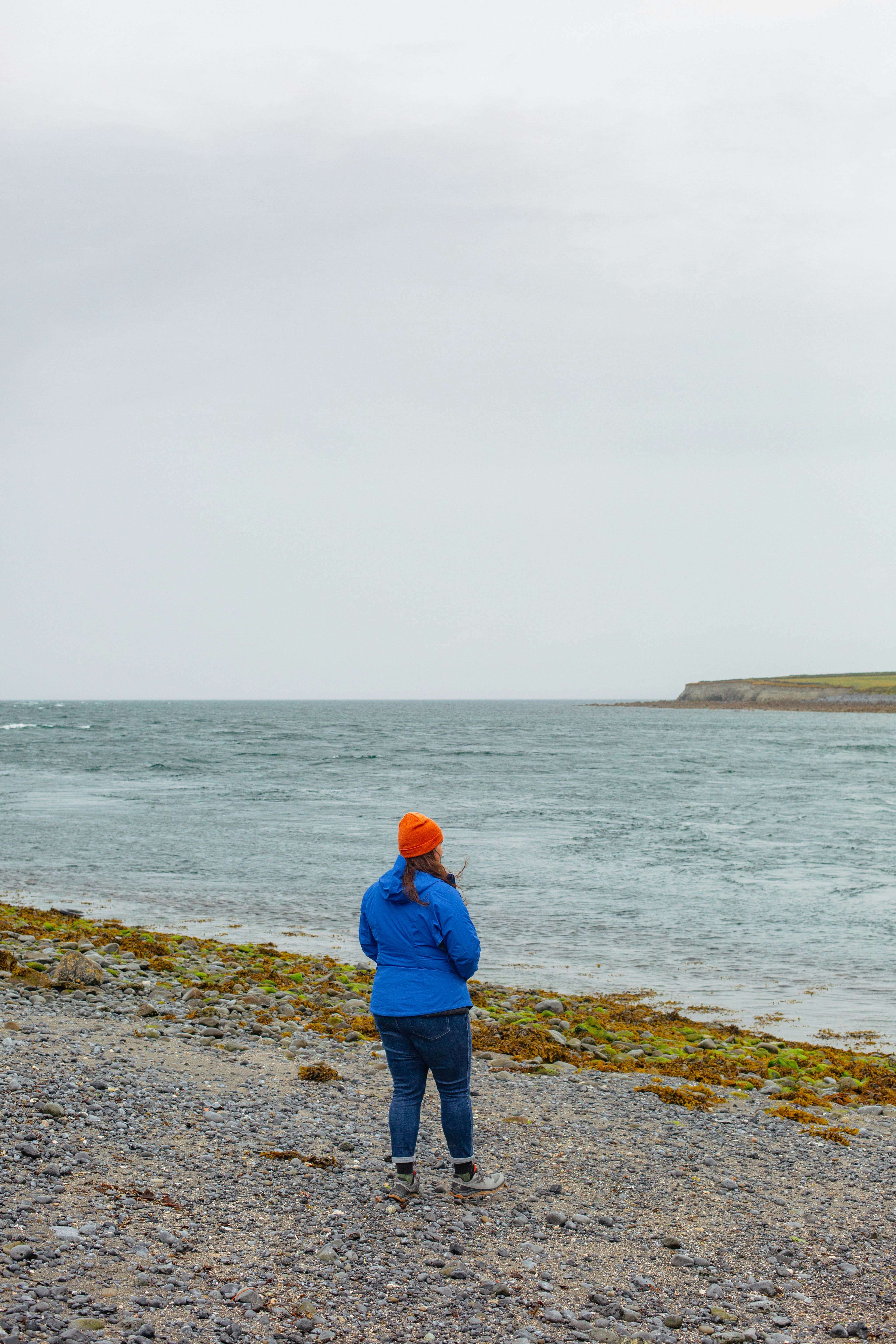 a person standing on a beach flying a kite