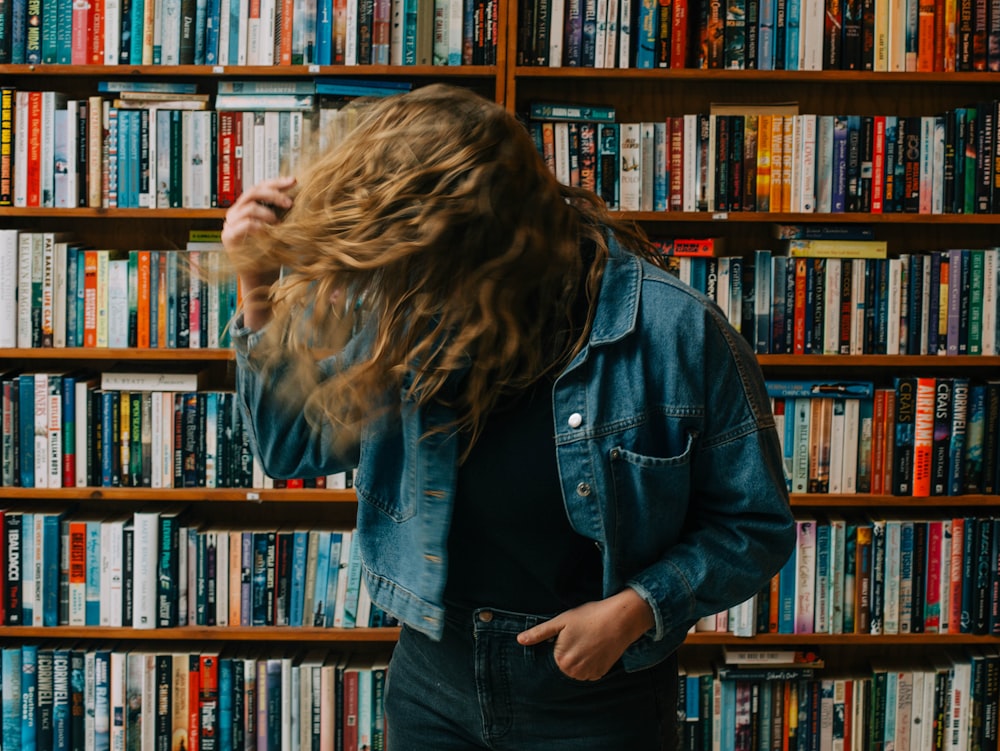 a woman standing in front of a bookshelf full of books