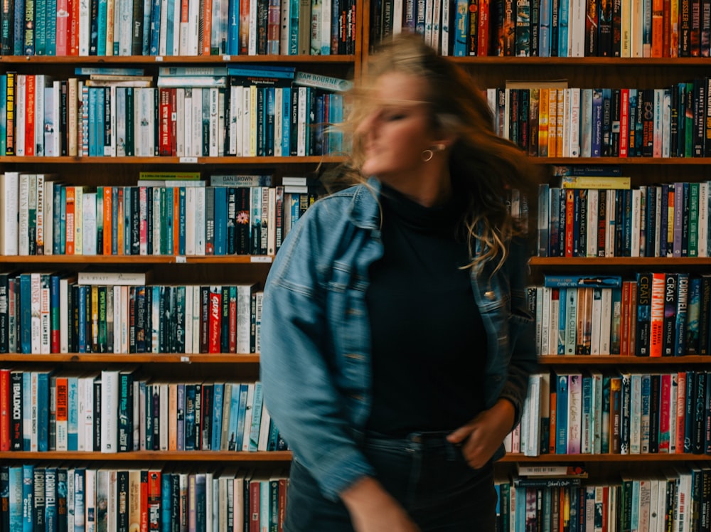 a woman standing in front of a bookshelf full of books