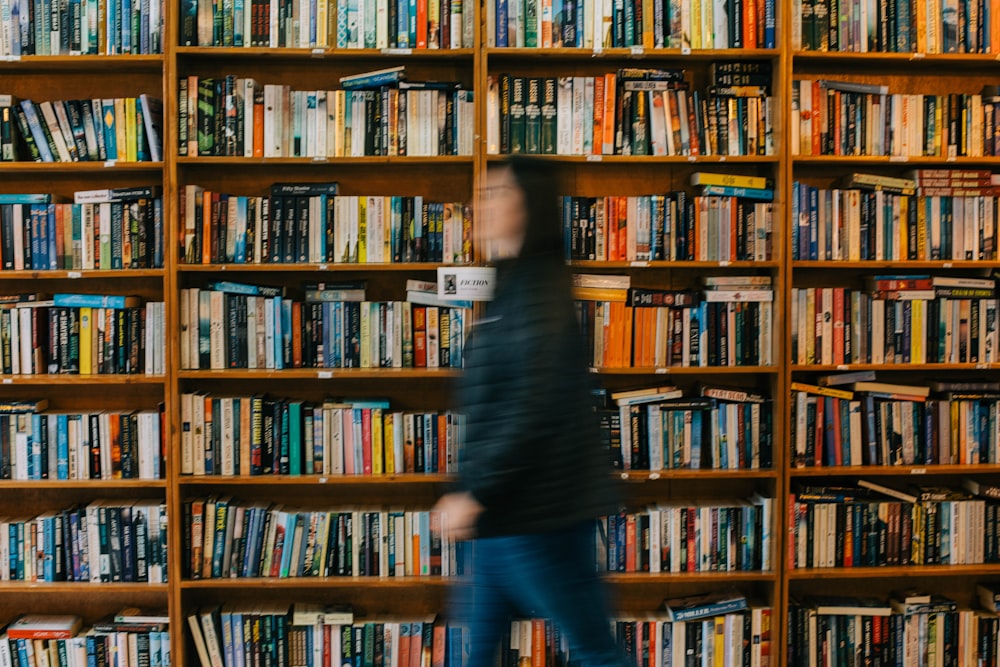 a blurry photo of a person walking in front of a bookshelf
