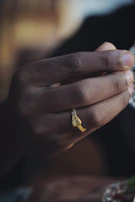 Hands gently holding a kundalini serpent symbol carved in black stone with cosmic light reflections.