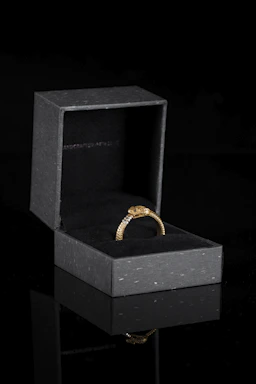 Close-up of an elegant gold ring with intricate detailing on a dark velvet background