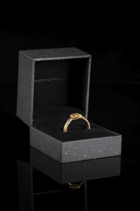Close-up of an elegant gold ring with intricate detailing on a dark velvet background