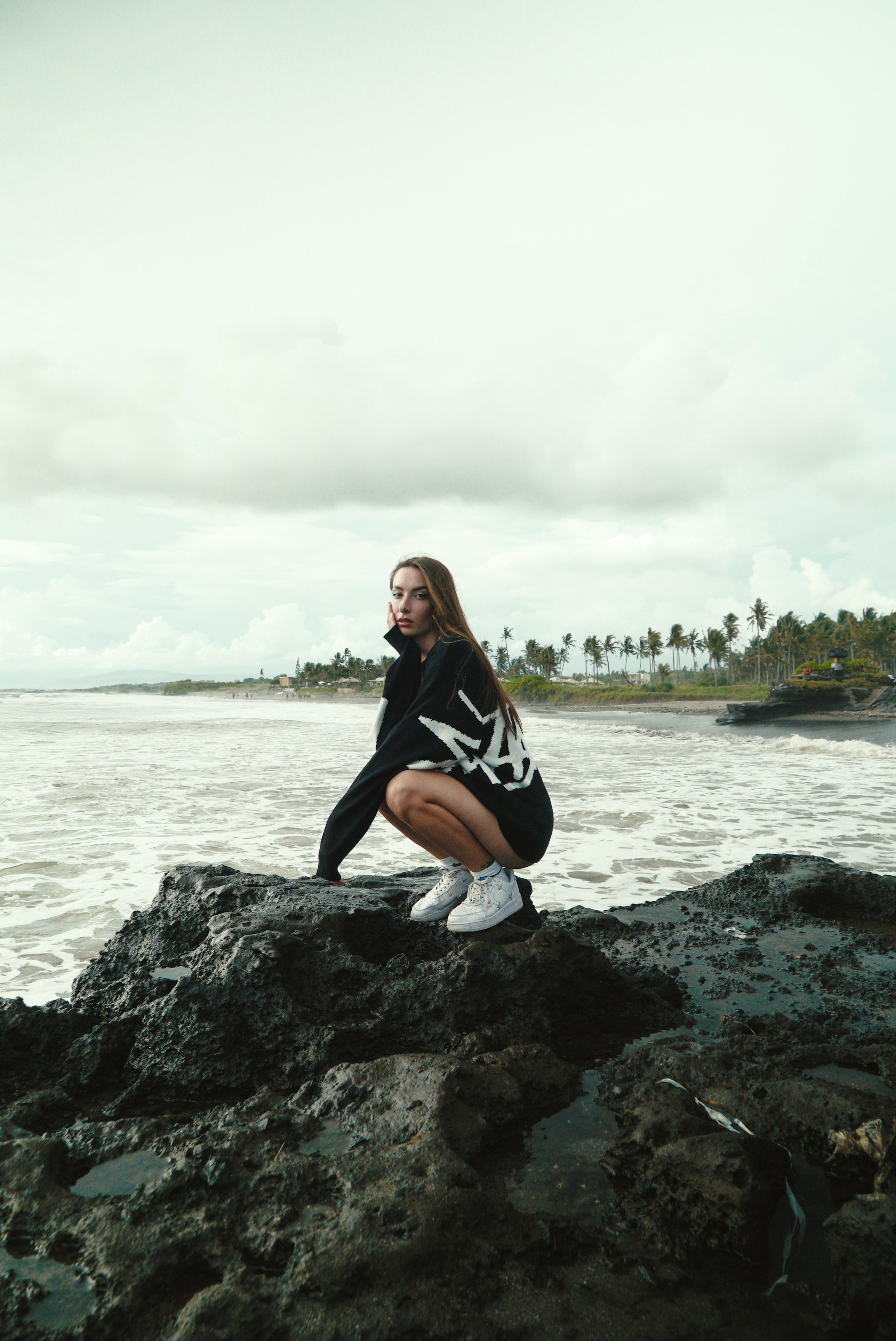 a woman sitting on top of a rock next to a body of water