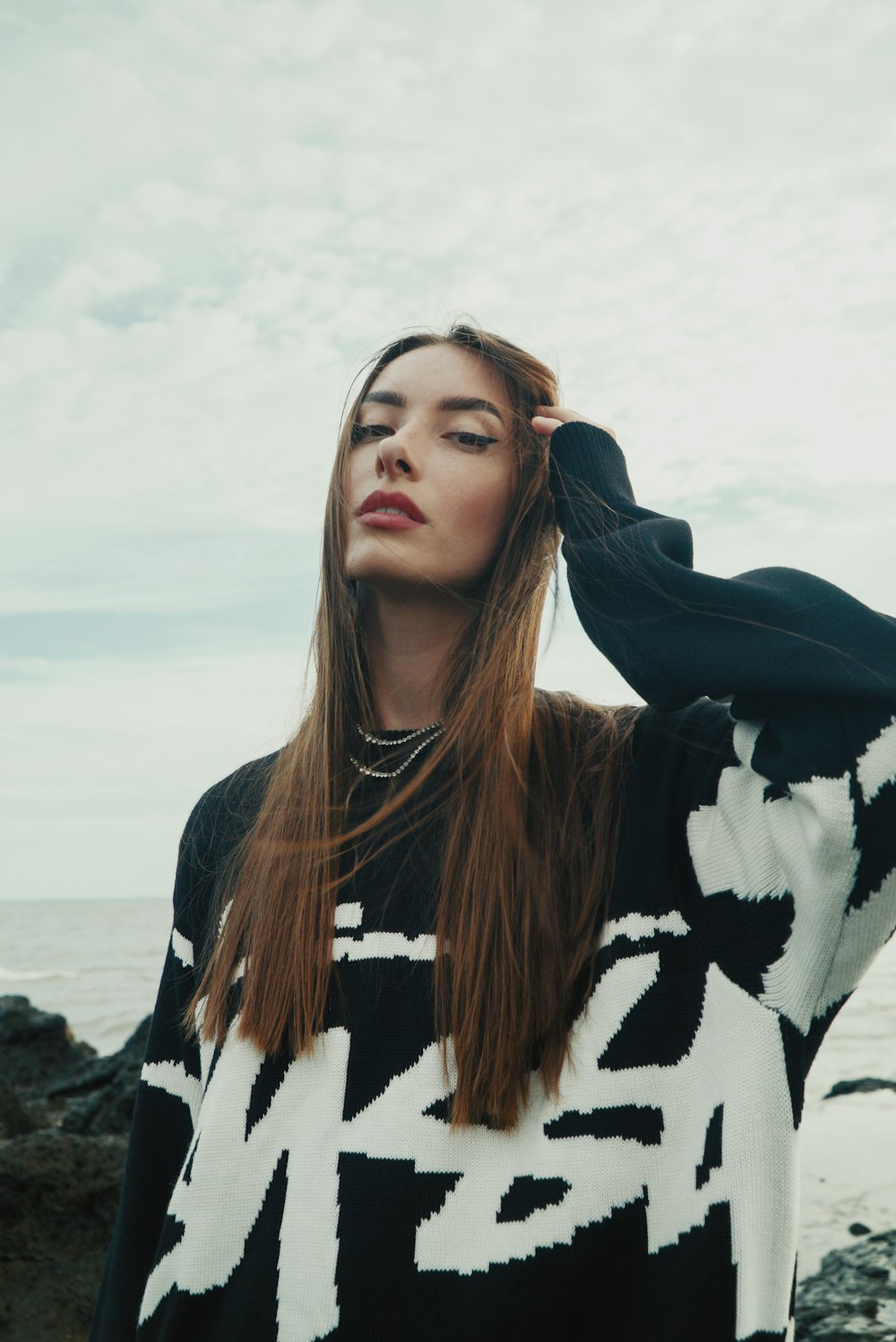 a woman with long hair standing near the ocean