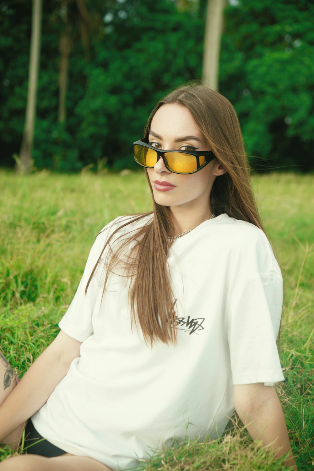 a woman wearing sunglasses sitting in the grass