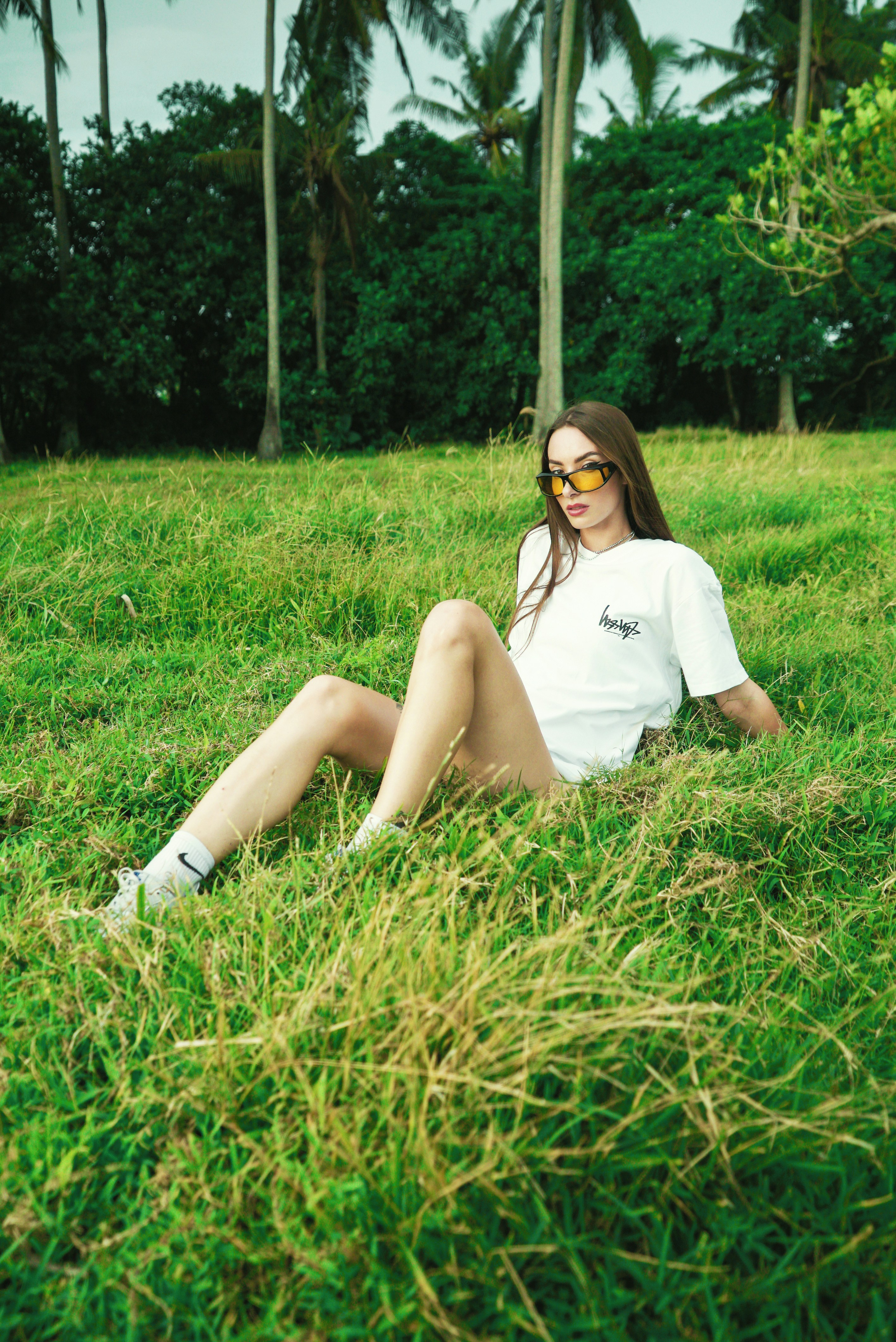 A woman sitting in the grass wearing sunglasses