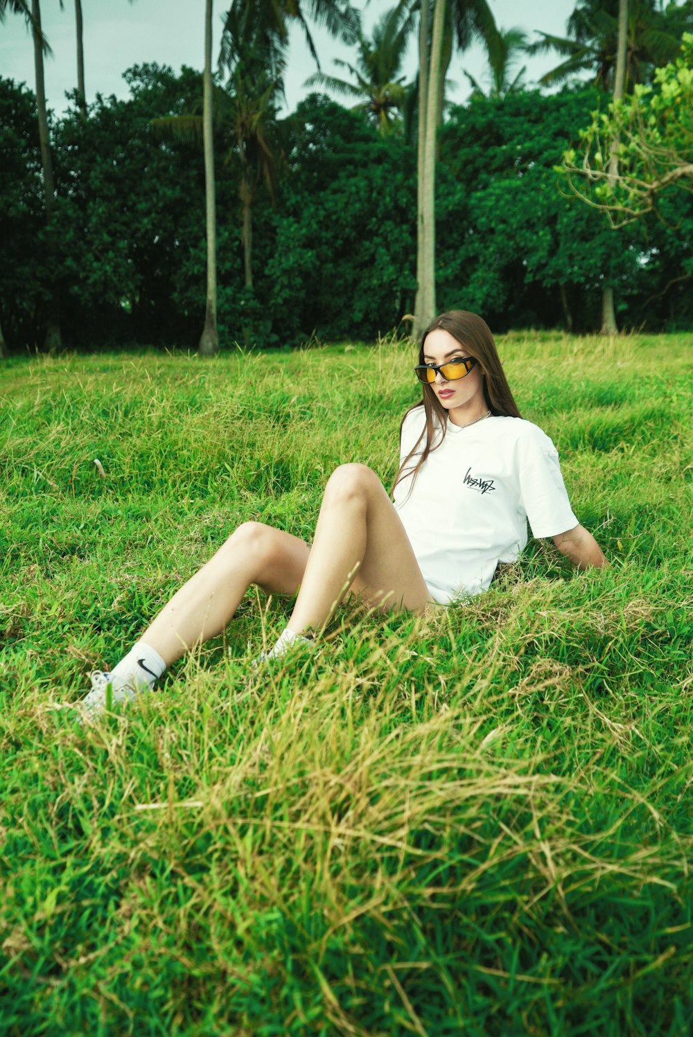 a woman sitting in the grass wearing sunglasses