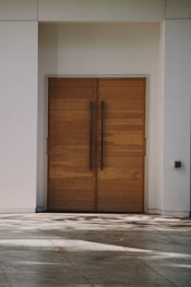 a pair of wooden doors in front of a white building