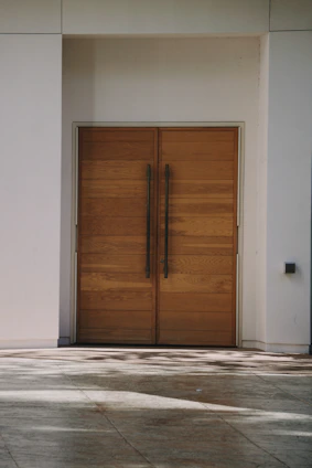 a pair of wooden doors in front of a white building