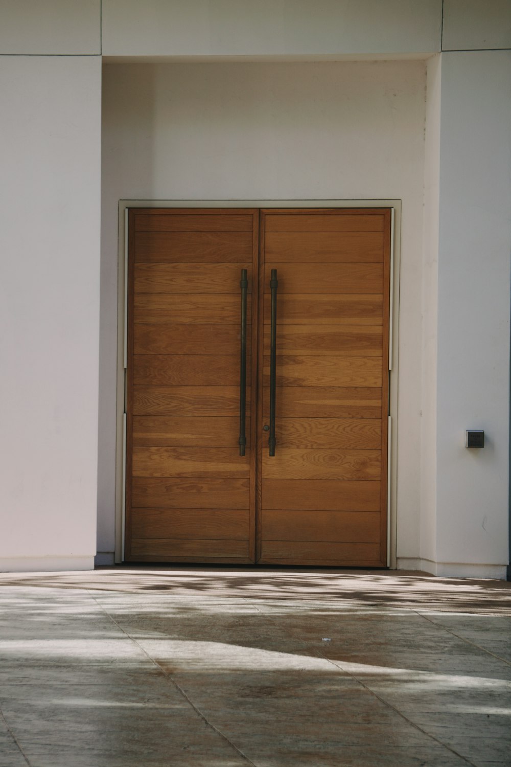 a pair of wooden doors in front of a white building