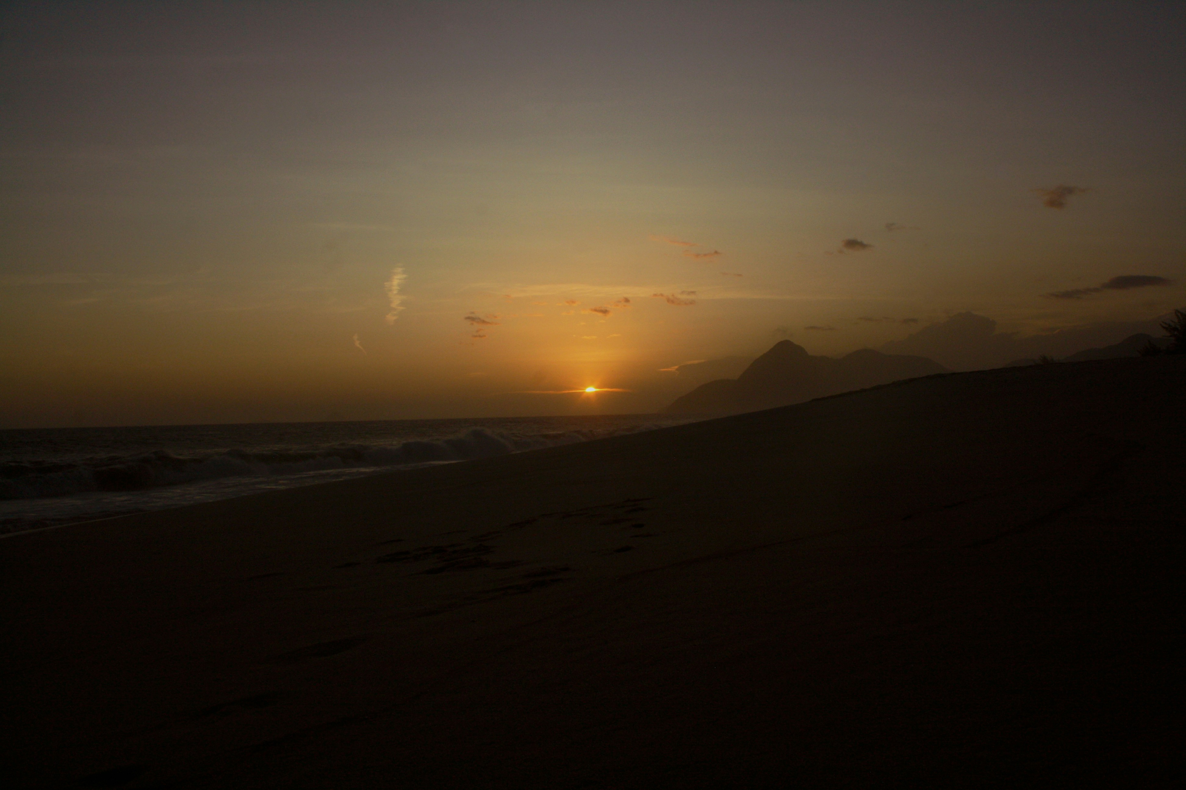 the sun is setting over the ocean on the beach