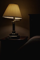 A bedside table with a unique sculptural lamp glowing softly against a neutral wall.