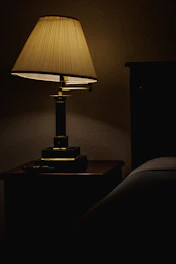 Narrow buffet table lamp casting a soft glow on a wooden sideboard.