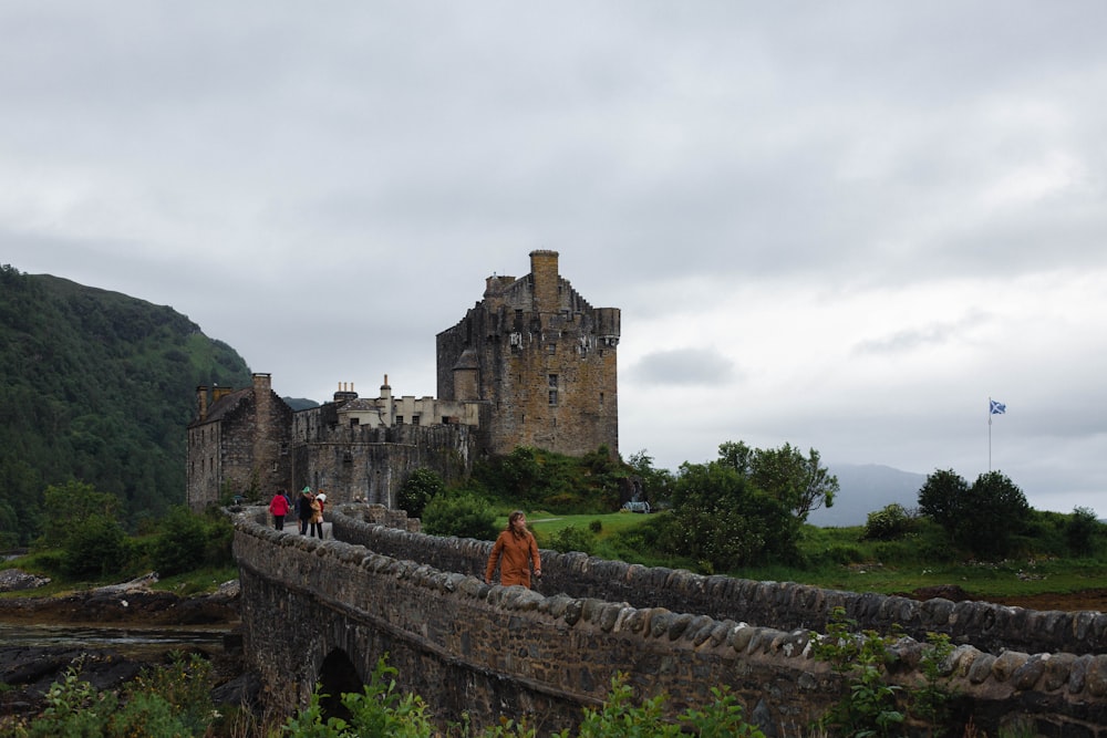 people walking on a bridge in front of a castle