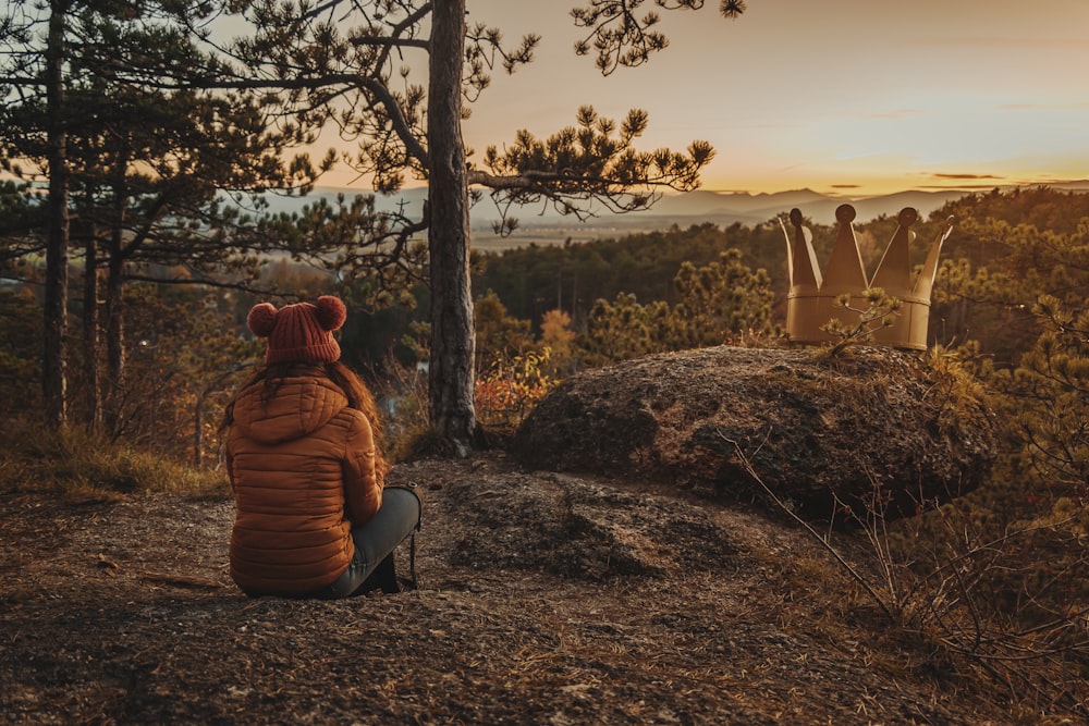 a person sitting on top of a hill next to a forest