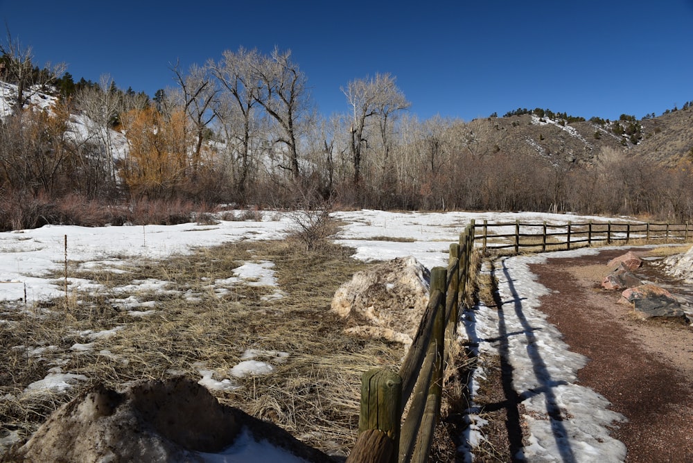 a wooden fence sitting next to a snow covered field