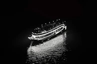 Nighttime shot of an aqua current boat illuminated with soft turquoise lighting on the water.