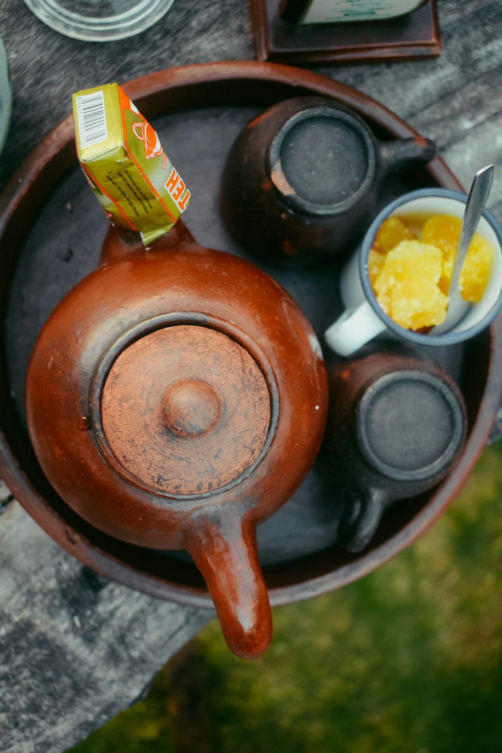 a tea pot with a cup of tea and a carton of orange juice