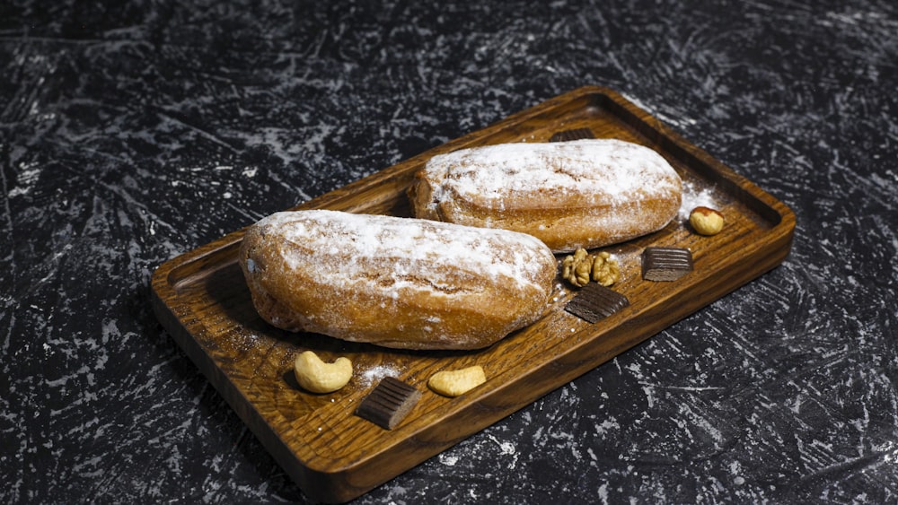 two pastries on a wooden tray with nuts and chocolate