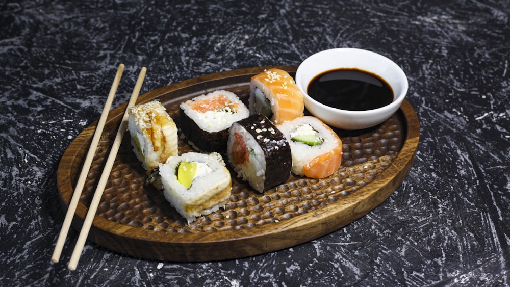 a plate of sushi with chopsticks and a cup of coffee