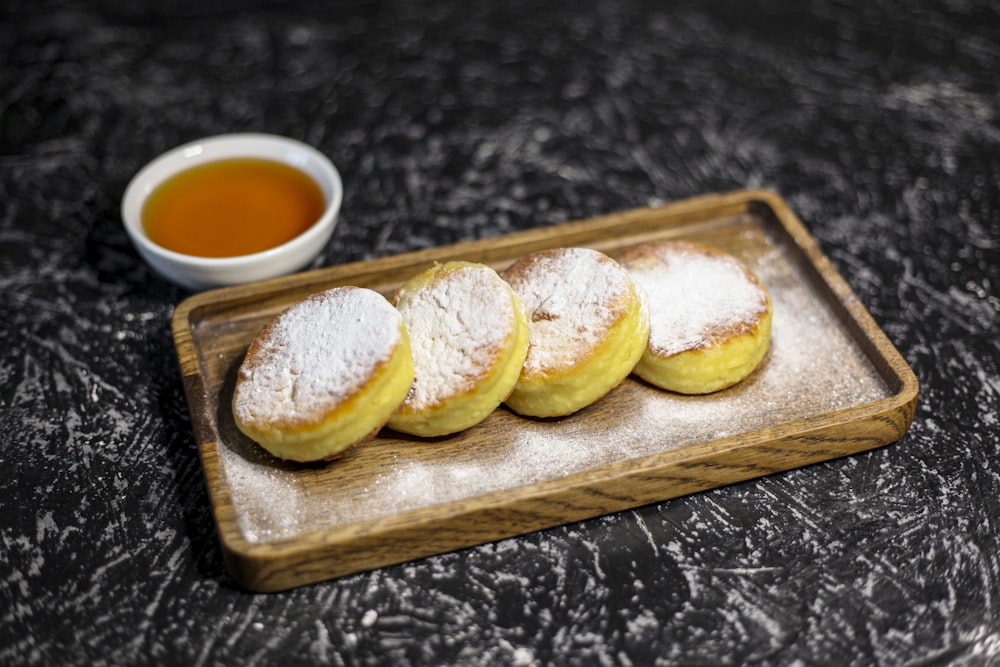 a wooden tray topped with pastries next to a cup of tea