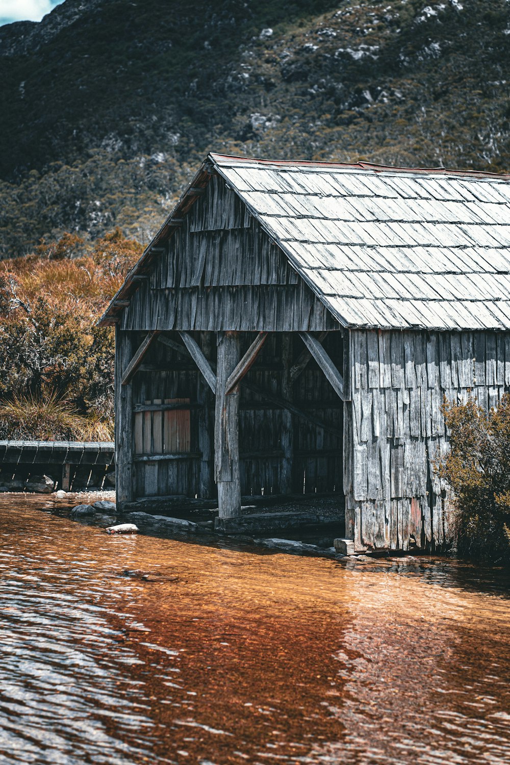 a wooden building sitting in the middle of a body of water