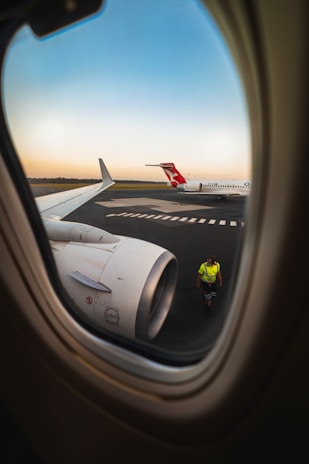 A pilot waving from the cockpit window as the plane taxis on the runway.