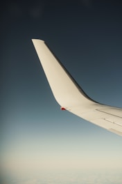 A close-up of a sleek ultralight aircraft wing against a clear blue sky.