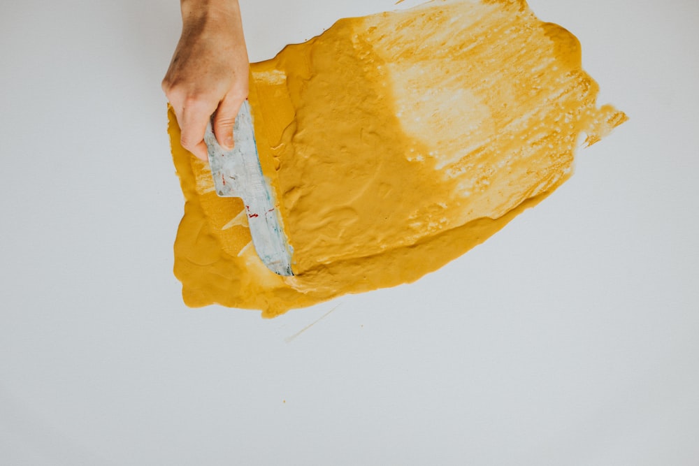 a person using a knife to cut a piece of yellow paper